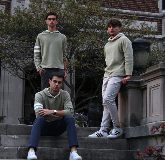 Three friends on stone steps wearing Captain's Pullover Hoodies in Sicilian Moss