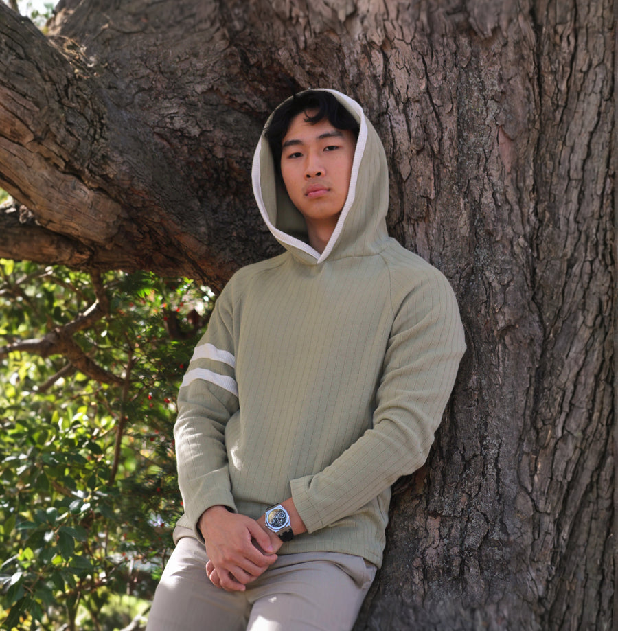 Man in a Sicilian Moss Captain's Pullover Hoodie leaning against a tree