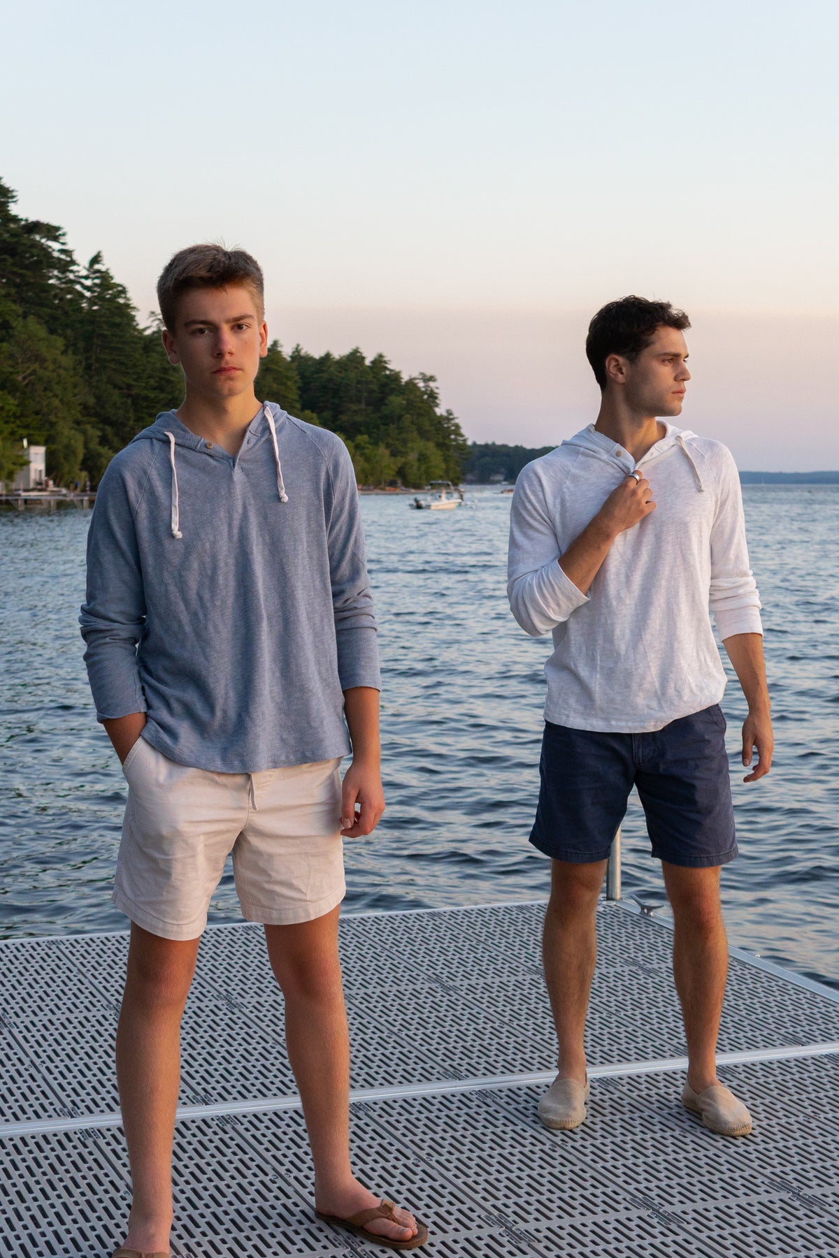 Two friends on a lake dock, one in a Captain's Blue BreezeWeight Pullover Hoodie and shorts