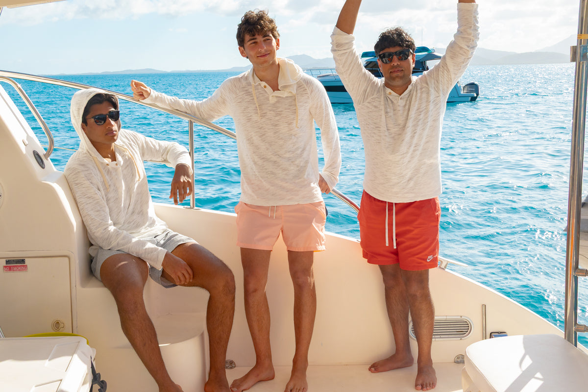 Three friends on a boat deck in Pearle BreezeWeight Pullover Hoodies