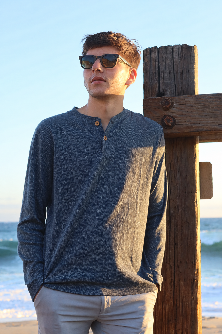 Herringbone Henley in Steel Blue with olive wood buttons, worn by the ocean